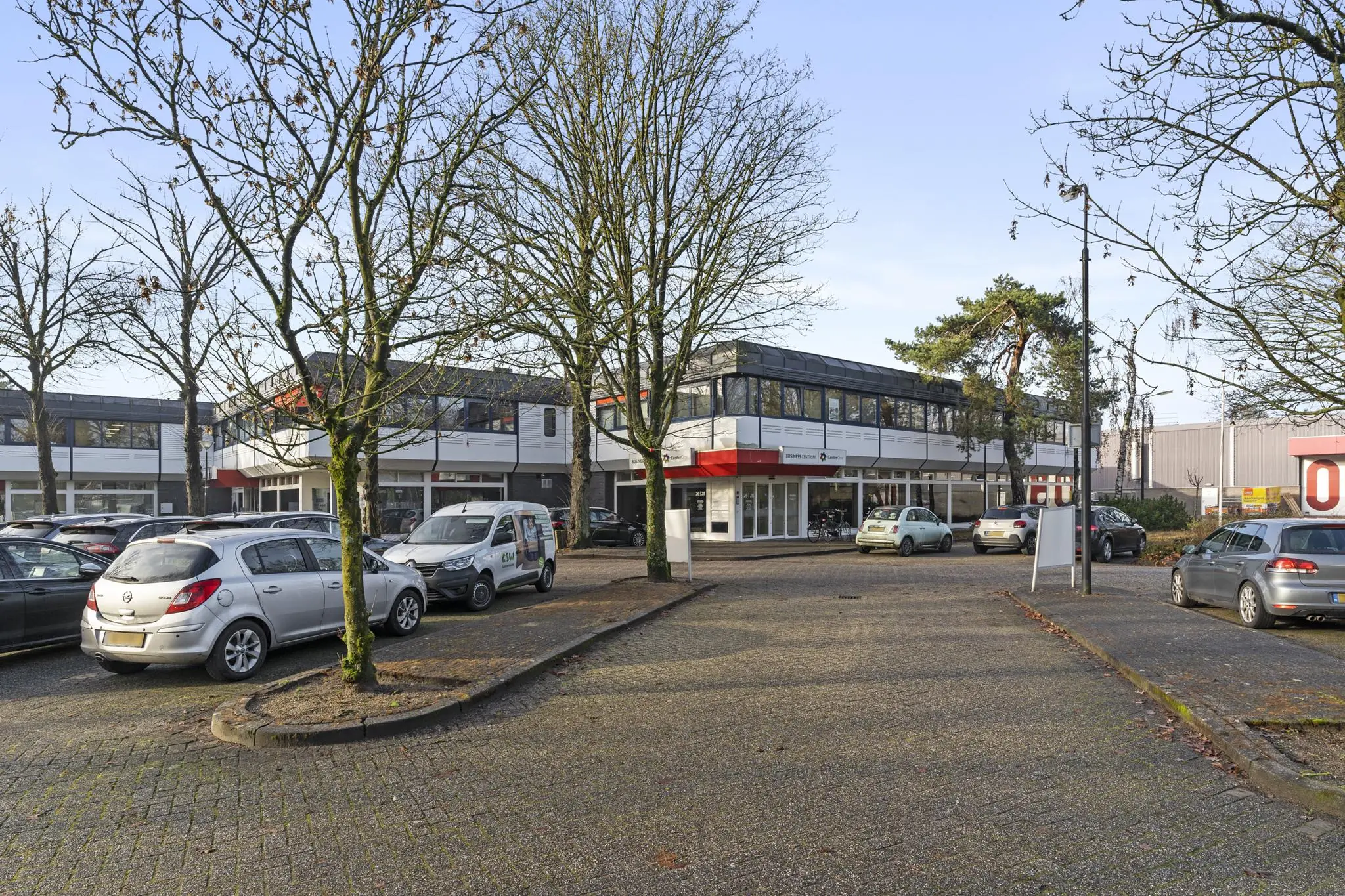 Bedrijfsverzamelgebouw aan de Huis-ter-Heideweg met geparkeerde auto's op een boomrijke parkeerplaats.